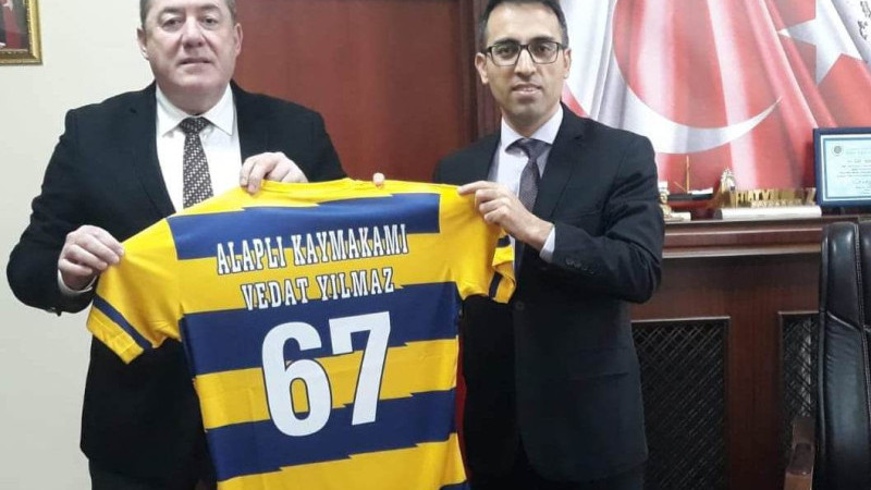 BAŞKAN TEKİN, KAYMAKAM YILMAZ’A ALAPLI BELEDİYE SPOR FORMASI HEDİYE ETTİ.